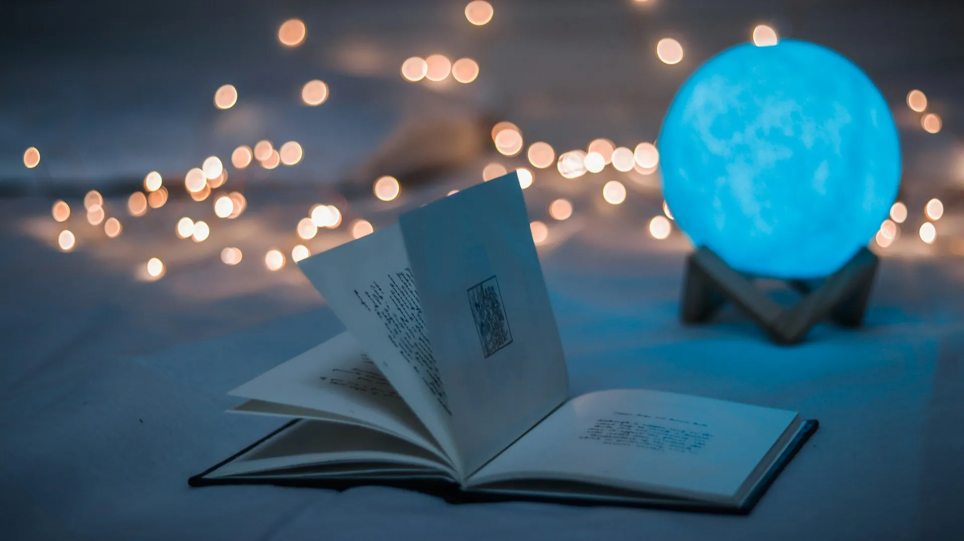 Photograph of an open book on a table with light glittering out and up from the pages
